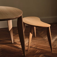 Light wood furniture featuring smooth finishes and elegant curves, set against a warm, patterned hardwood floor.
