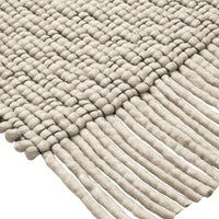 Textured beige woven rug with fringe detail, showcasing a patterned design of loops and lines. Perfect for any decor.