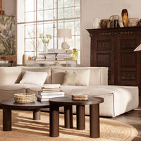 Soft beige sofa with cream cushions, dark wood tables, and a natural woven rug, complemented by a light, airy room decor.