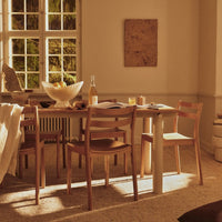 Light wood dining table and chairs with neutral tones, warm sunlight, and soft textures creating a cozy atmosphere.