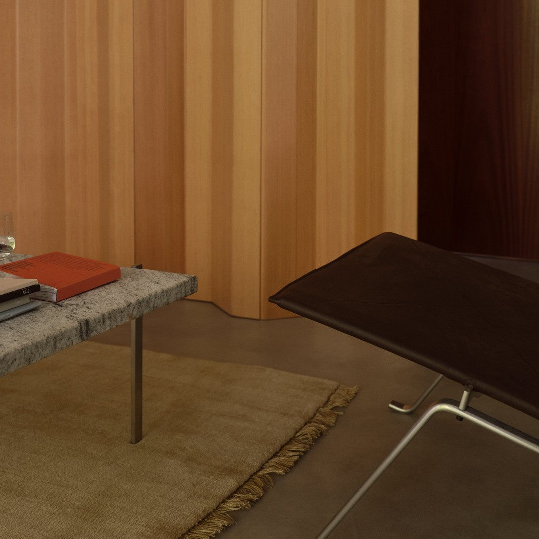 Gray marble coffee table on beige rug, surrounded by warm wood paneling in rich brown and soft beige tones.