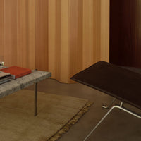 Gray marble coffee table on beige rug, surrounded by warm wood paneling in rich brown and soft beige tones.