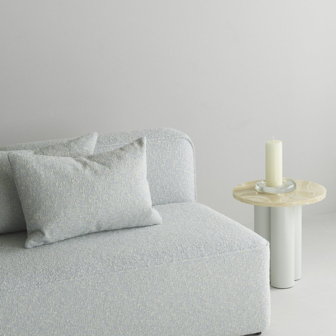 Light blue textured couch with cream accents and decorative pillows, paired with a minimalist light wood side table.