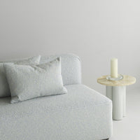 Light blue textured couch with cream accents and decorative pillows, paired with a minimalist light wood side table.