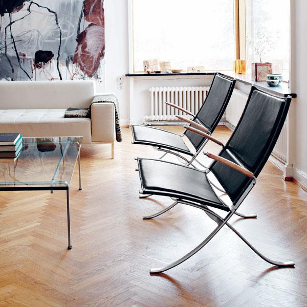 Modern black leather chairs with sleek silver frames, set against a light wood floor and minimalist decor.