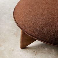 Brown textured ottoman with a smooth finish and wooden legs, ideal for modern interior decor.