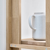 White speckled ceramic jug on a natural wood shelf with clean lines and simple aesthetics.