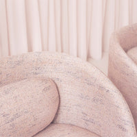 Textured pink upholstery featuring subtle speckles in pastel hues. Soft curves complement a warm, inviting aesthetic.