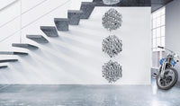 Modern wall art in silver tones with intricate patterns, placed against a white wall and gray stair backdrop.