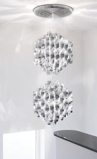 Elegant dual crystal pendant lights with intricate geometric patterns in clear glass against a white backdrop.