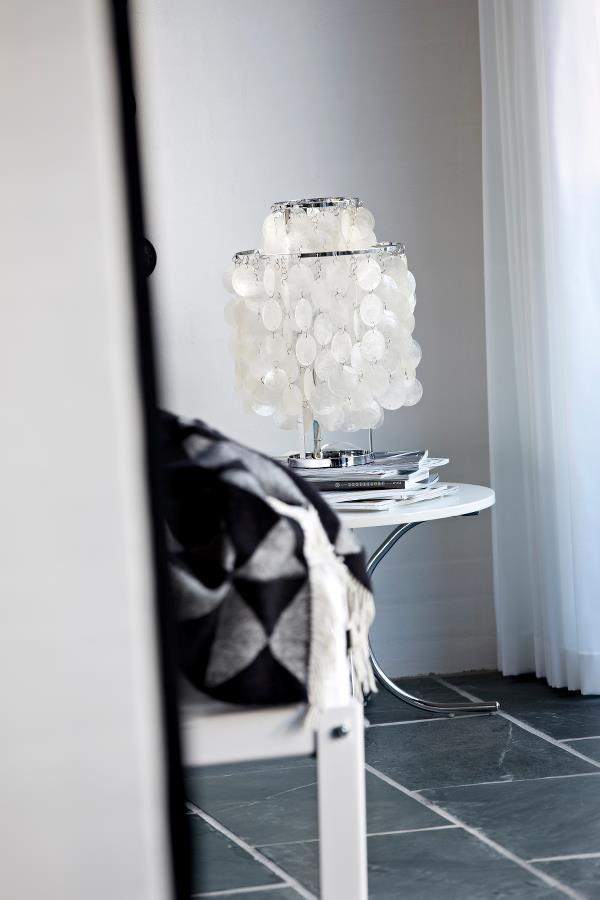 "Elegant white lamp with circular shades on a sleek white table, complemented by a patterned black and white throw."