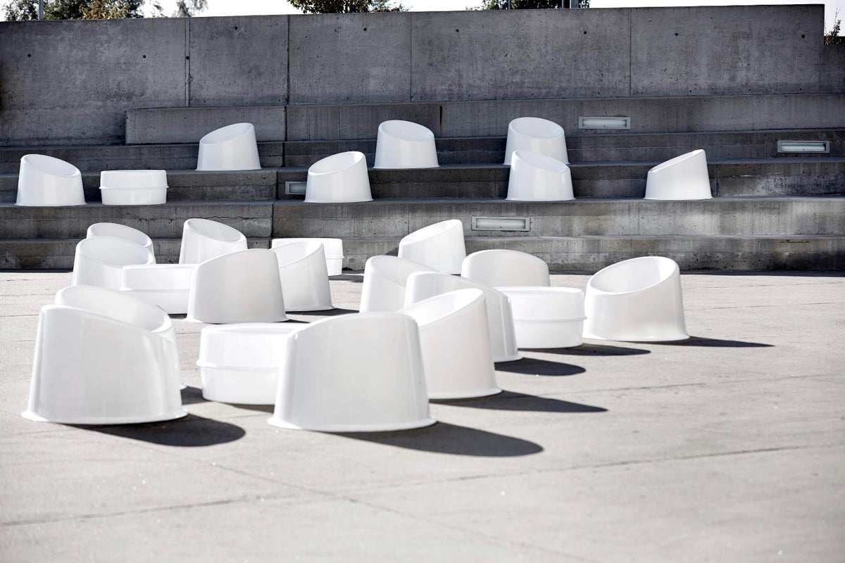 White, minimalist seating scattered on a concrete surface, creating a modern, geometric pattern.