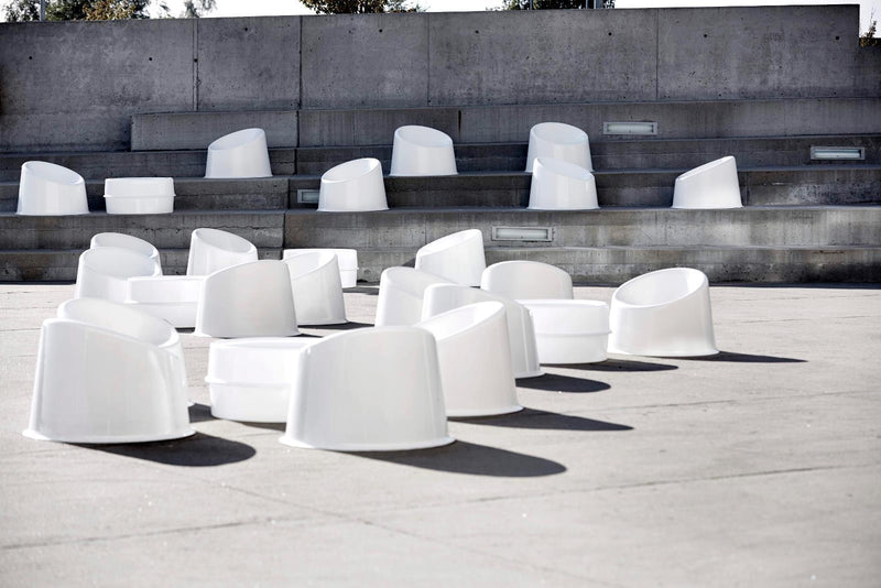 White, minimalist seating scattered on a concrete surface, creating a modern, geometric pattern.