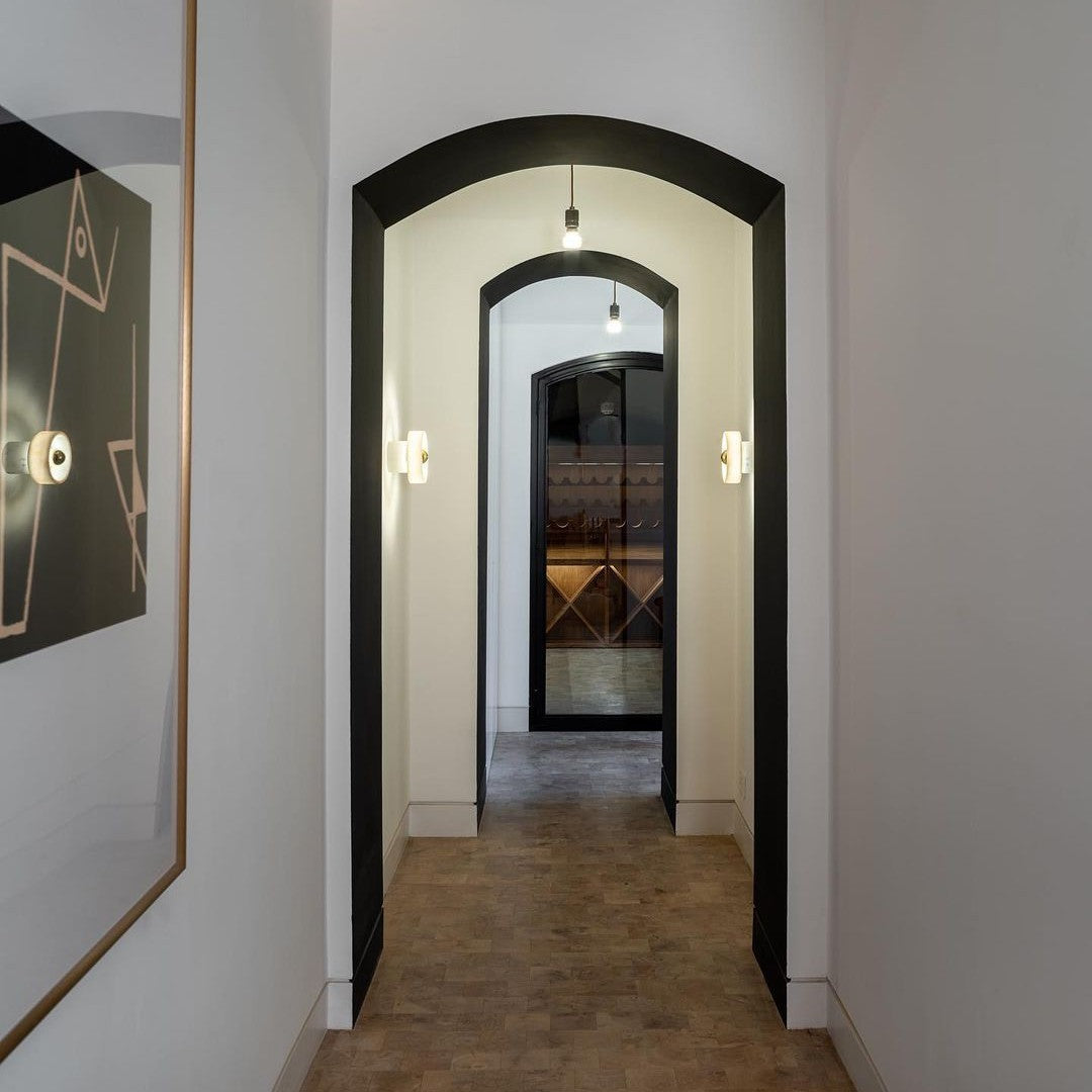 Hallway featuring sleek black arches, warm wood tones, and geometric wall art in a minimalist design.