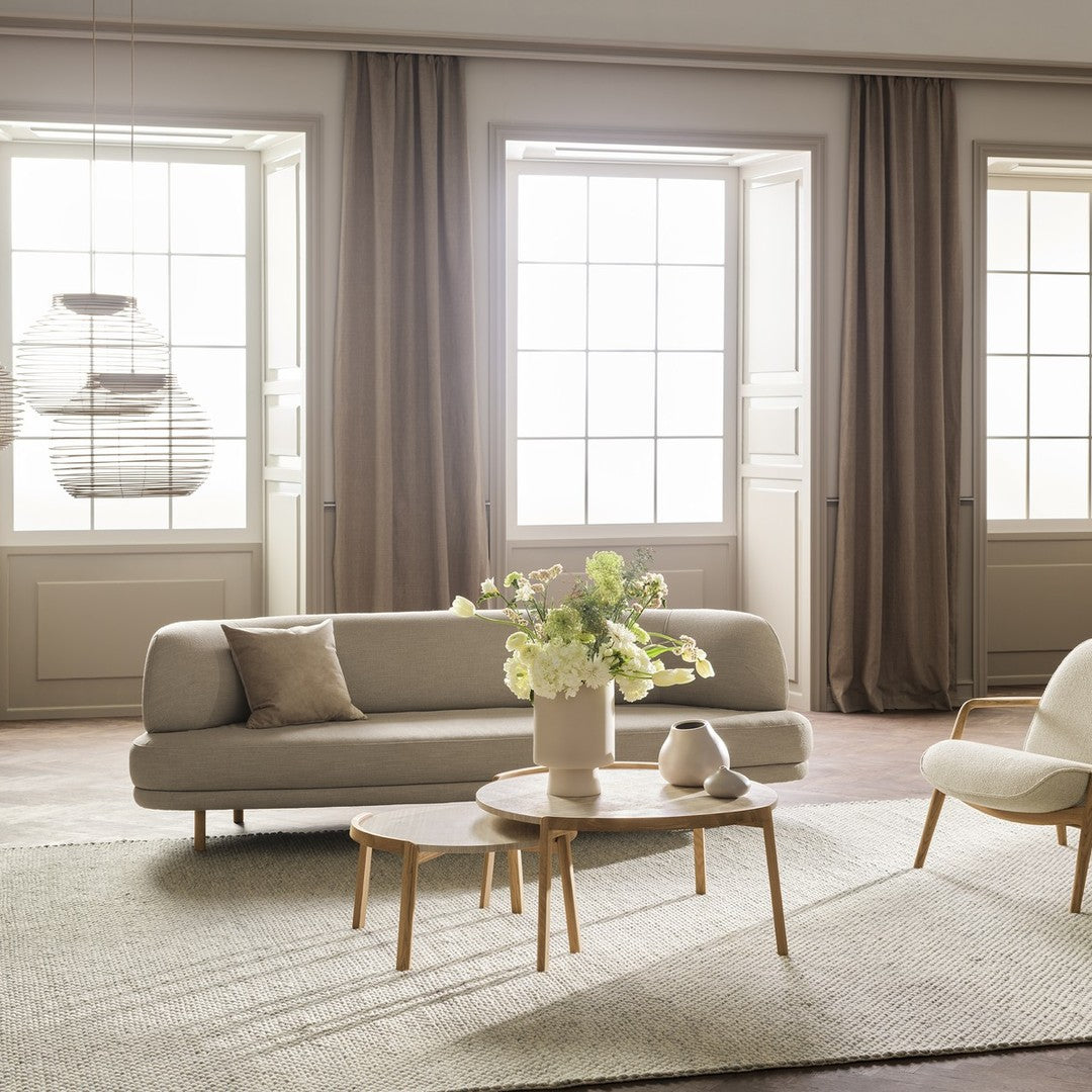 Light beige sofa with neutral accents, soft gray rug, and earthy wooden furniture, complemented by soft natural lighting.