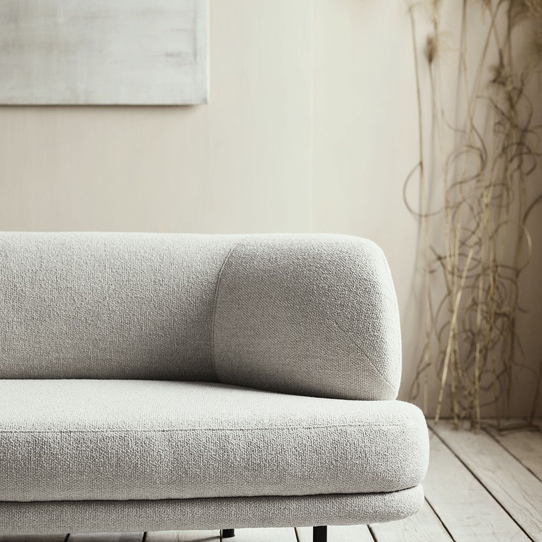 Light grey sofa with a soft, textured fabric and smooth, rounded armrest on a natural wood floor.