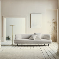 Light grey sofa with smooth texture, complemented by neutral tones and soft patterns in a minimalist interior setting.