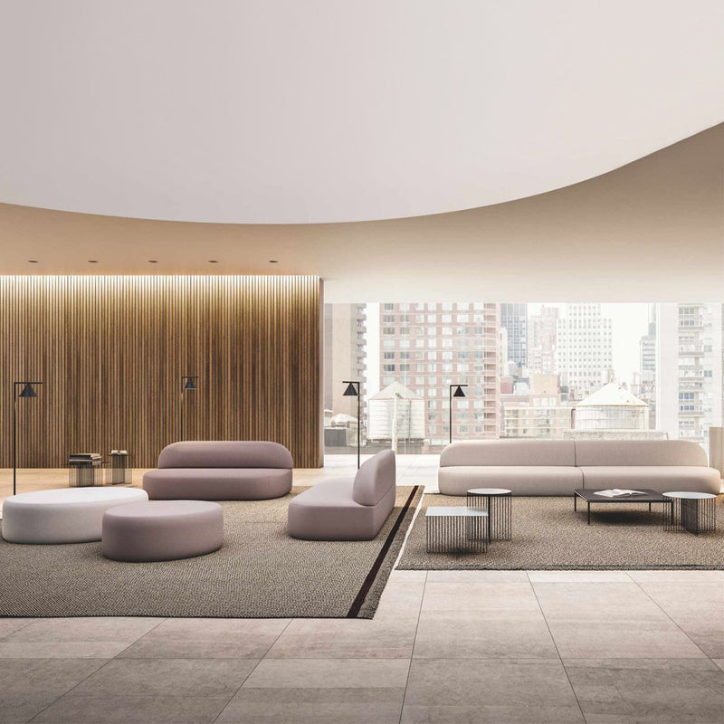 Stylish modern seating in soft pink and white tones, complemented by wood and neutral textured flooring.