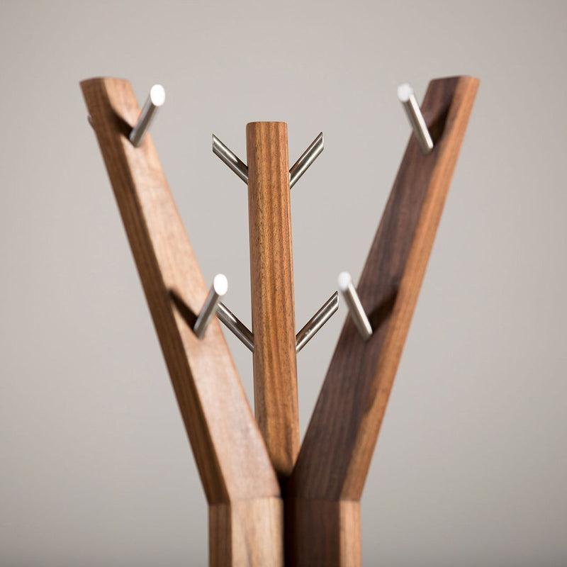 "Modern wooden coat rack with a natural finish and sleek silver hooks, featuring a minimalist geometric design."