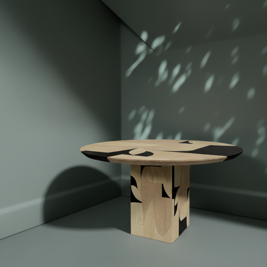 Modern round table with wood grain finish and bold black geometric patterns on a neutral background.