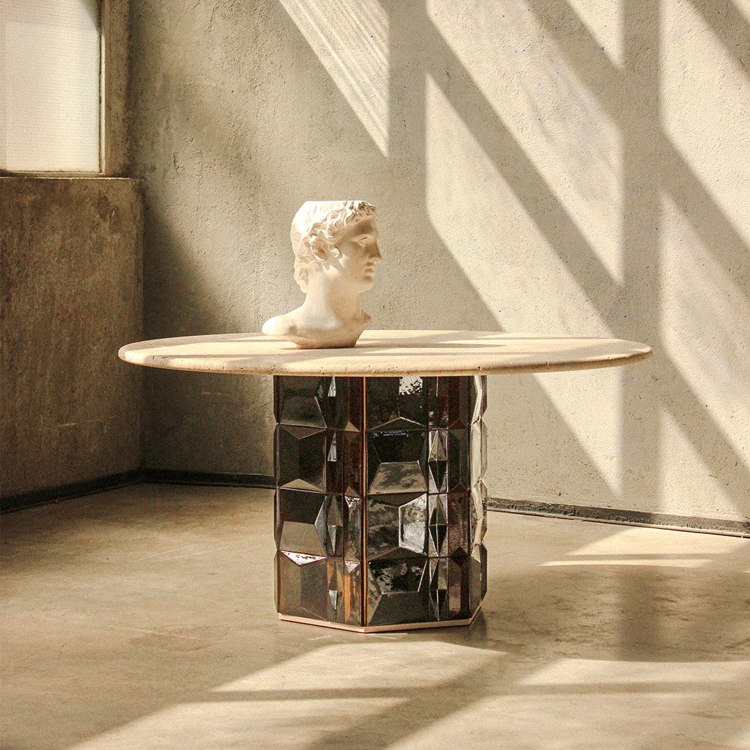 Elegant round table with a light wood top and a patterned black and silver geometric base. Ideal for modern decor.