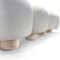 Soft gray plush upholstered mushrooms with textured tops and light beige stone bases, arranged in a row.