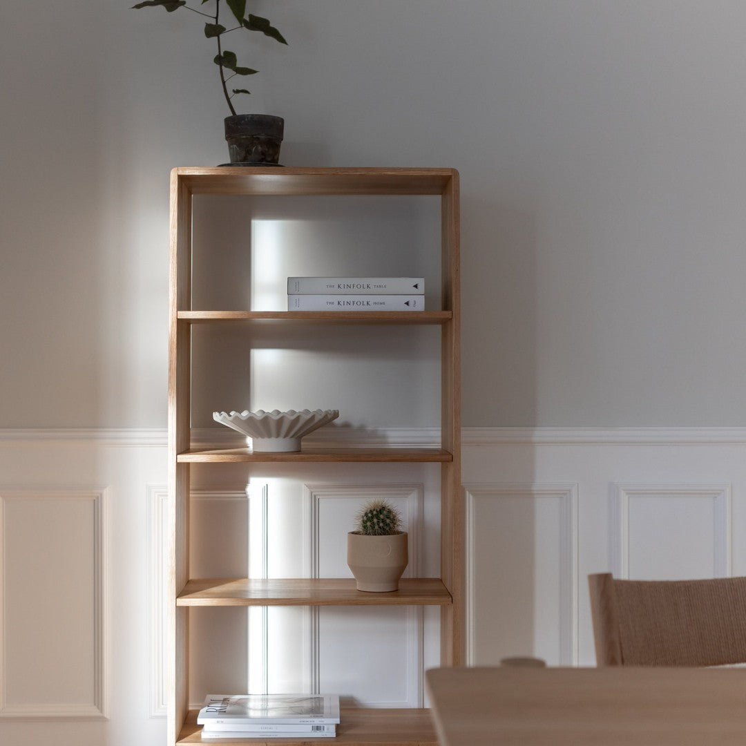 Natural wood bookshelf with a light finish, showcasing minimalist design against a soft gray wall.