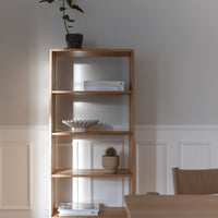 Natural wood bookshelf with a light finish, showcasing minimalist design against a soft gray wall.