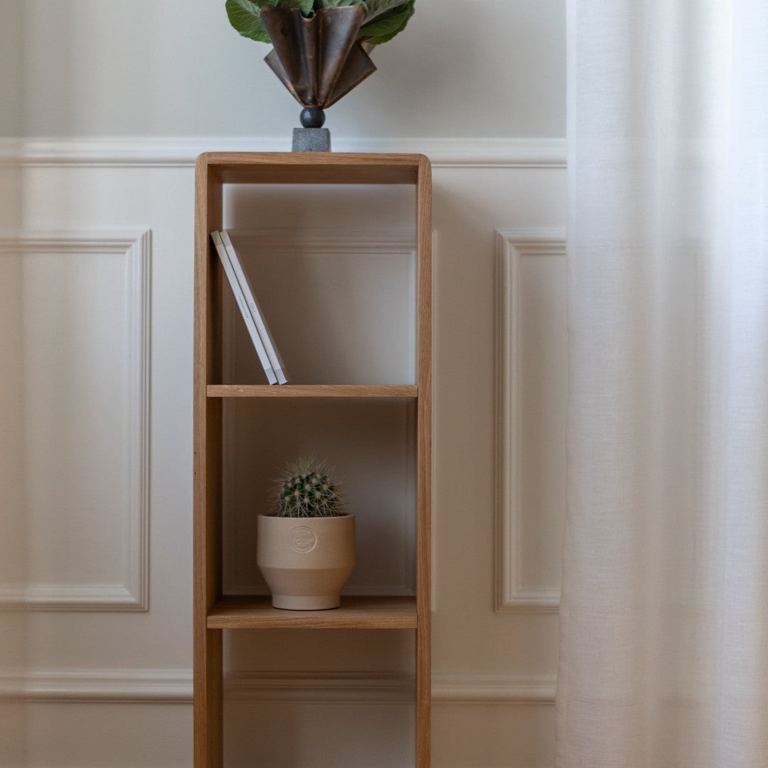 Natural wood bookshelf with minimalist design, featuring light tones and clean lines against a soft, neutral backdrop.