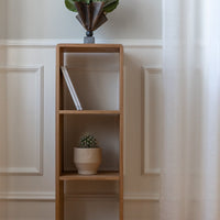 Natural wood bookshelf with minimalist design, featuring light tones and clean lines against a soft, neutral backdrop.