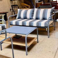 Blue and white striped sofa with matching accent cushions and a light blue coffee table on a neutral floor.