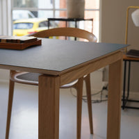 Modern wooden table with a dark grey top and natural oak legs, featuring a sleek, minimalist design.