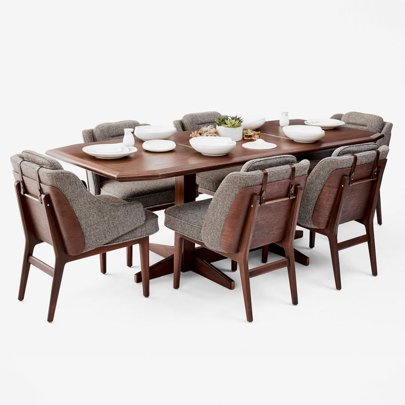 "Rectangular brown wooden dining table with eight gray patterned upholstered chairs."