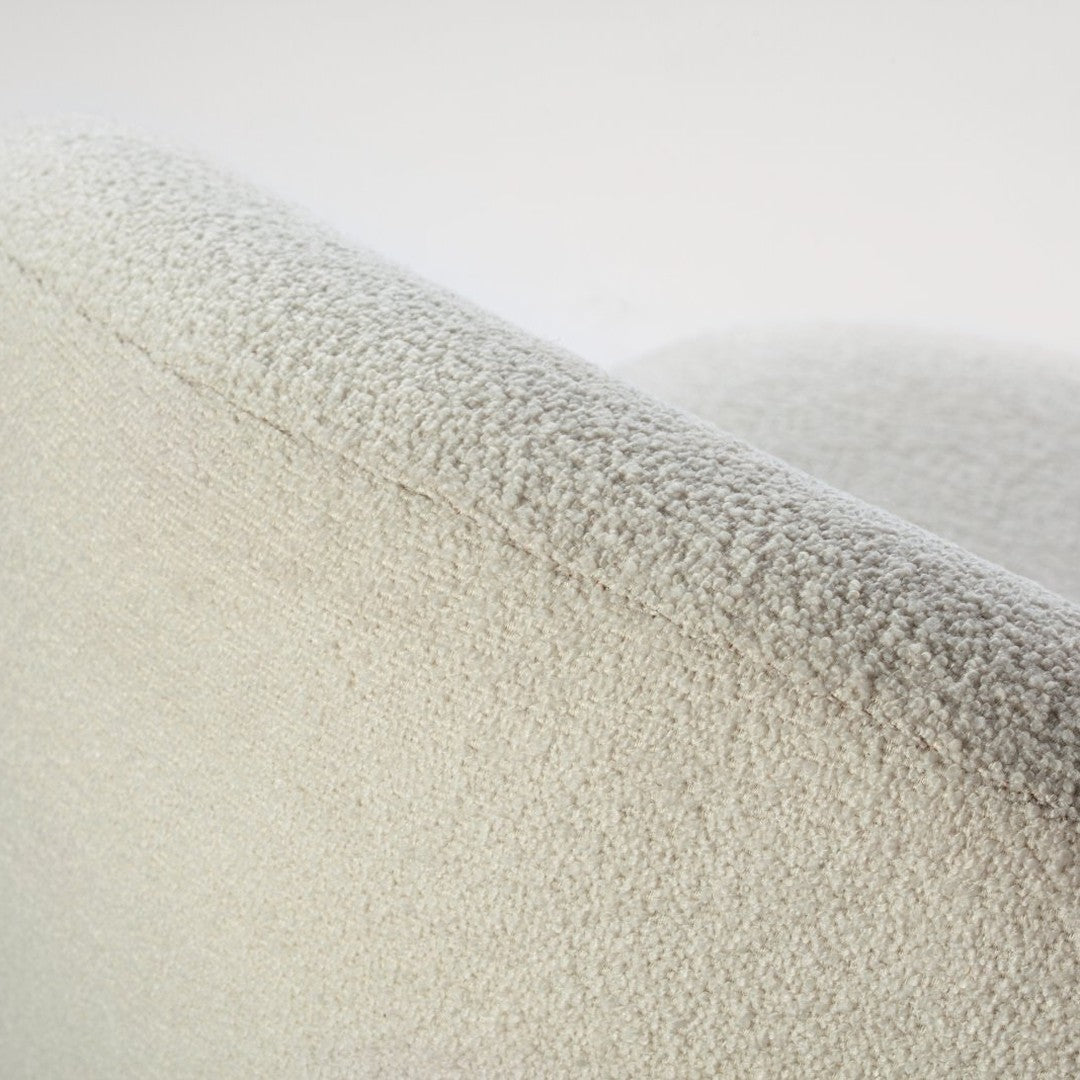 Soft ivory textured fabric with a subtle, cozy pattern on a modern curved sofa edge. 