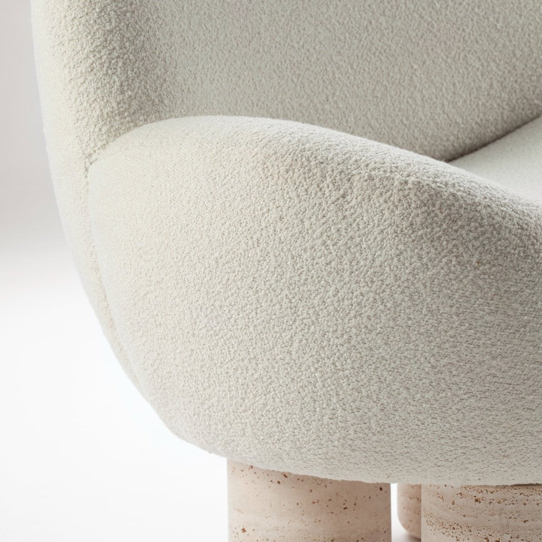 Light beige textured fabric armchair with soft, rounded edges and natural stone legs, adding warmth and elegance.