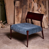 Mid-century modern chair with a rich mahogany frame and soft blue plush upholstery. Natural wood background enhances colors.