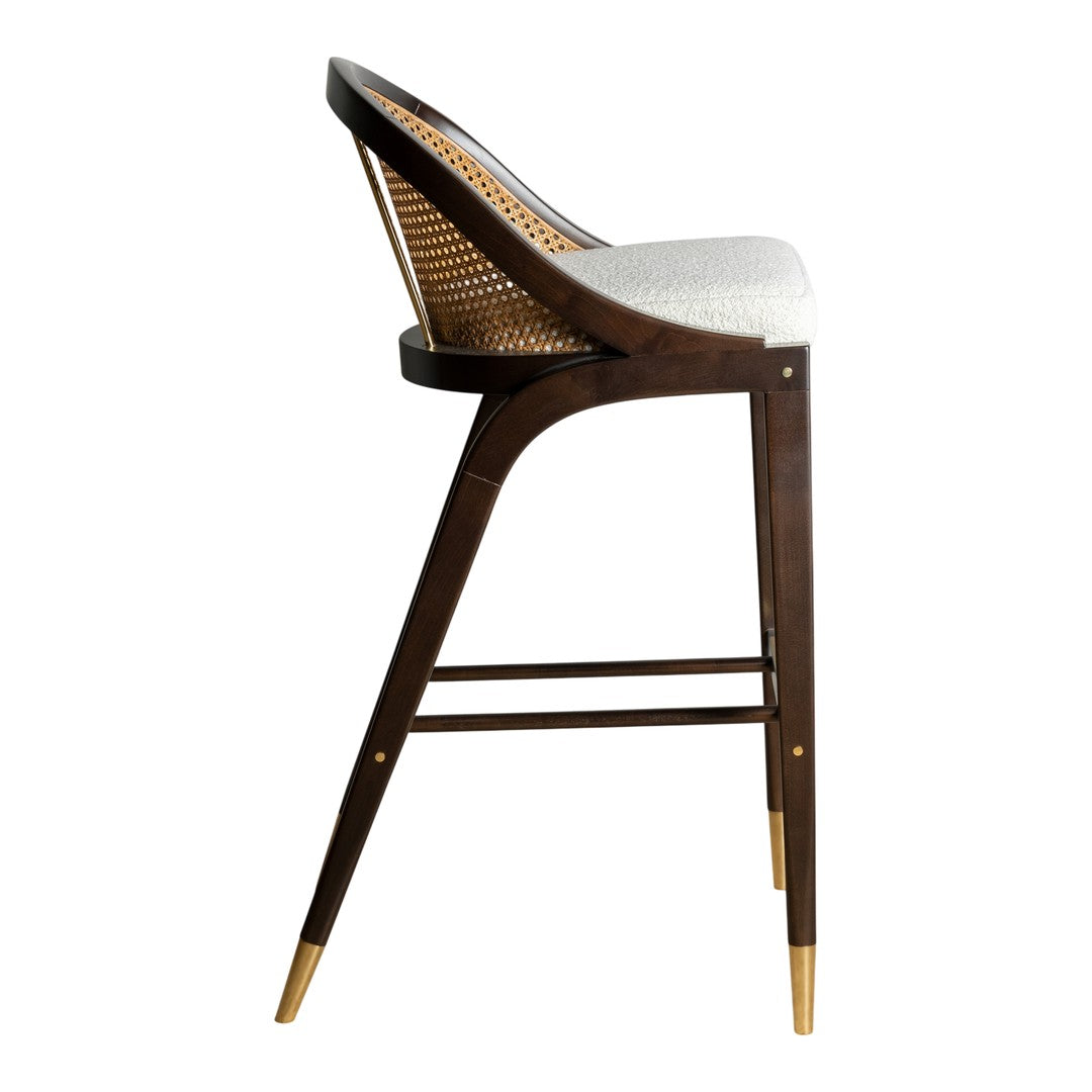 Dark wood bar stool with a natural woven back, white cushion, and gold-tipped legs, combining chic and modern design.