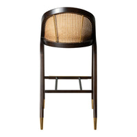 Dark wood bar stool with woven cane back and gold-tipped legs, featuring a sleek, modern design.