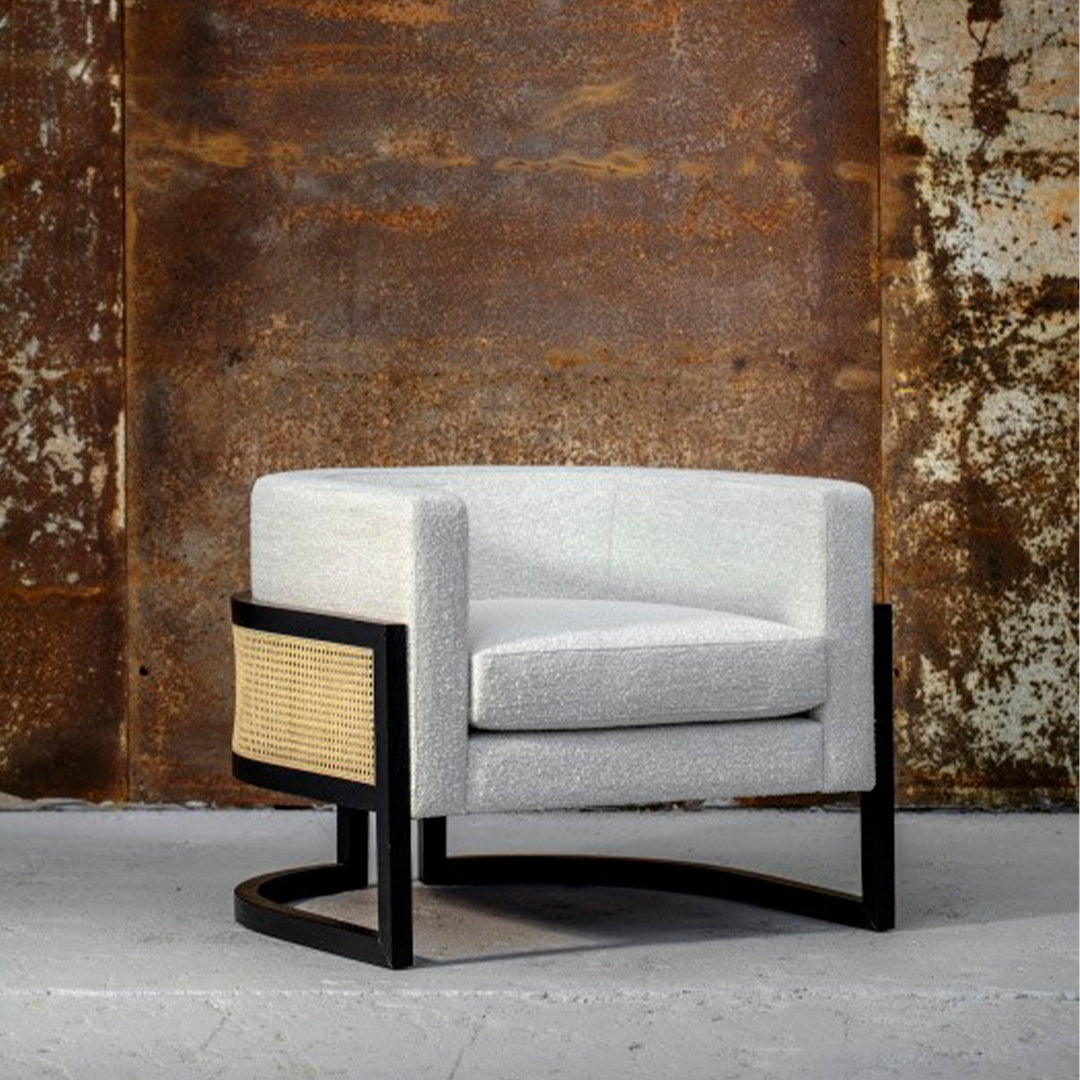 Stylish gray upholstered chair with a woven rattan side, featuring a sleek black frame. Modern design accent.