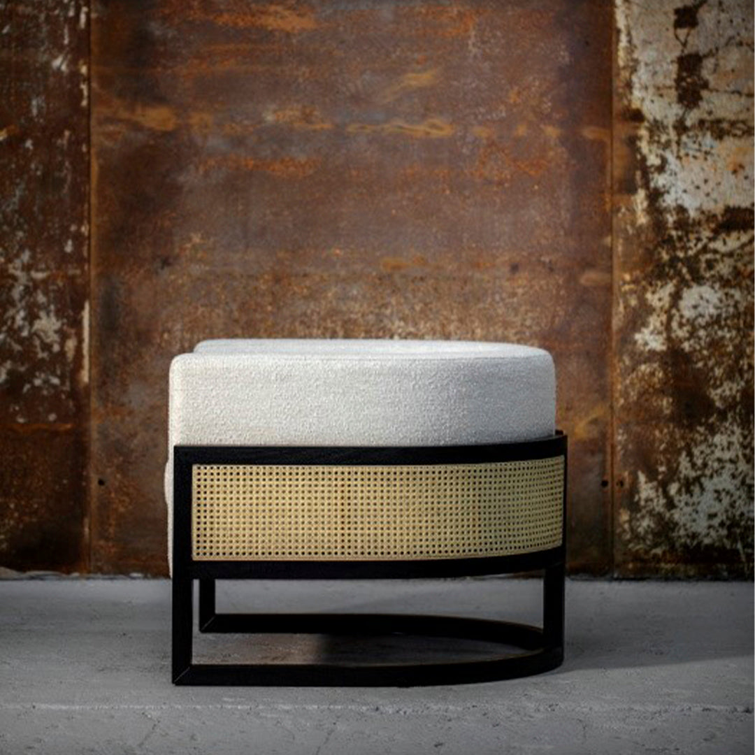 Modern upholstered ottoman in soft white with woven rattan accents and sleek black frame. Ideal for stylish interiors.