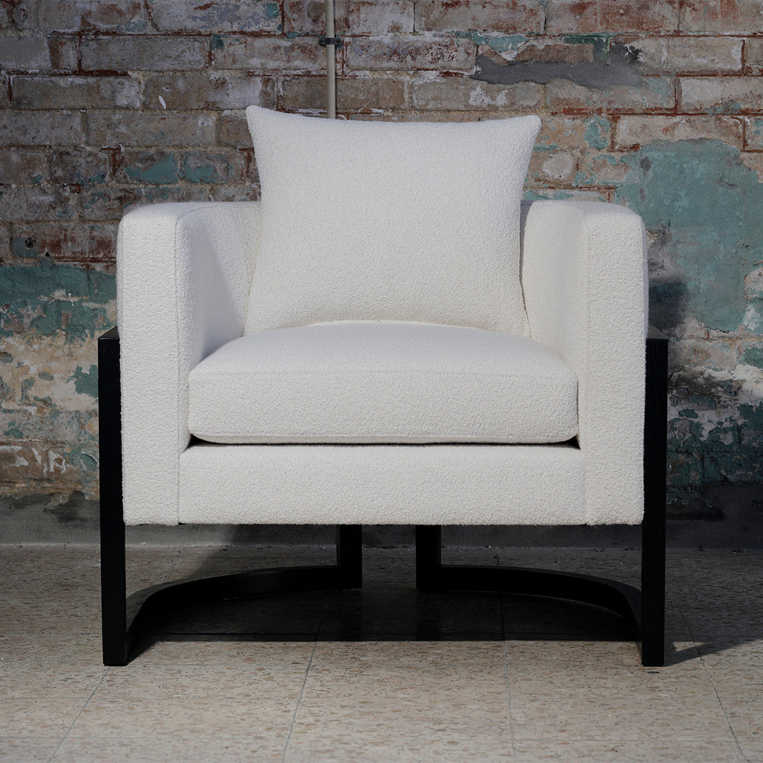 White upholstered chair with a solid black frame and a matching accent pillow, perfect for modern decor.