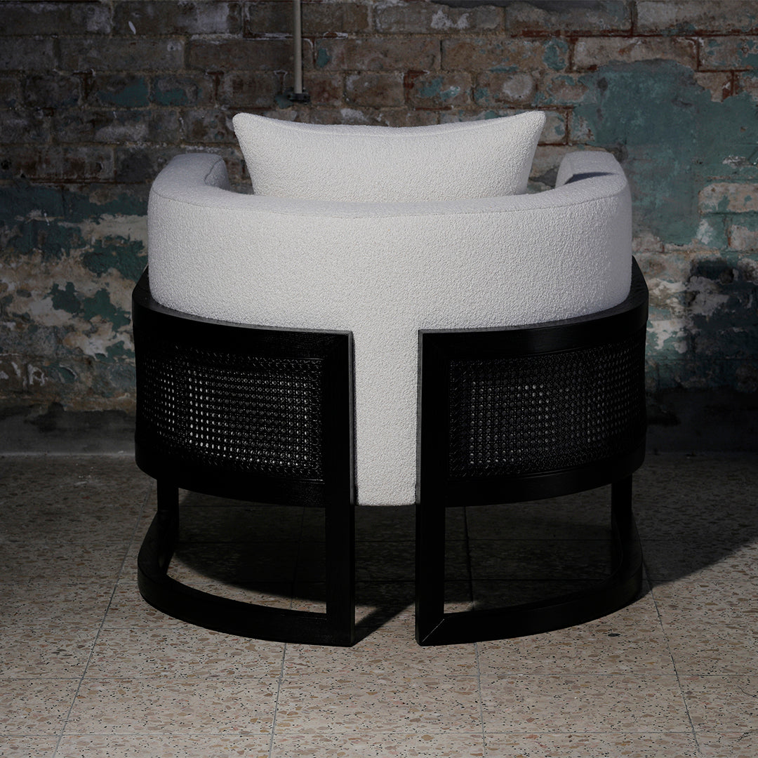 Modern round chair featuring a textured white cushion and sleek black rattan base. Ideal for stylish interiors.