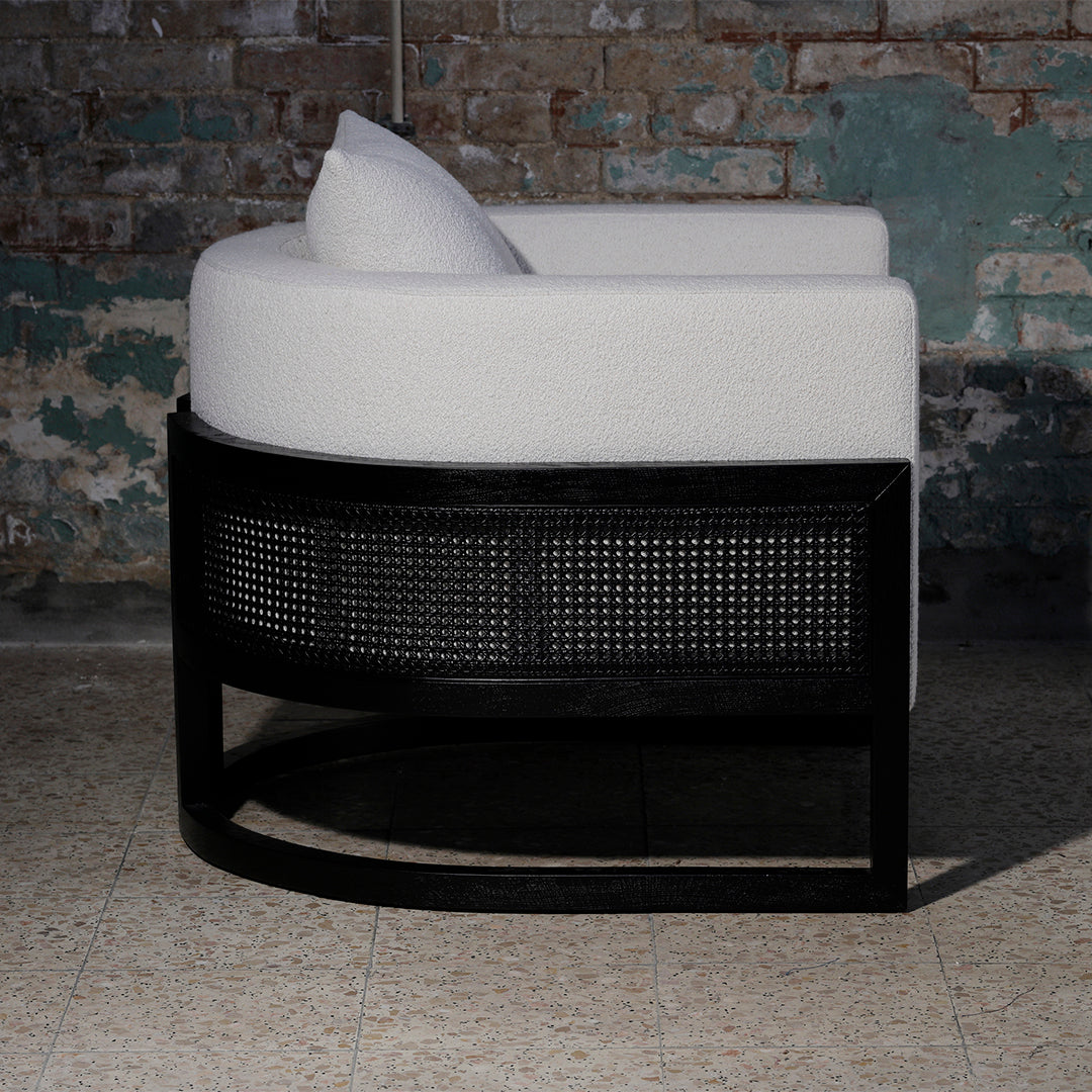 Curved white upholstered chair with a black woven rattan base, showcasing a modern and minimalist design.