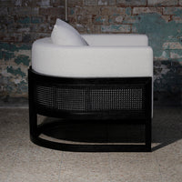 Curved white upholstered chair with a black woven rattan base, showcasing a modern and minimalist design.