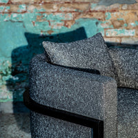 Stylish gray textured sofa with a sleek black frame, featuring a cozy patterned pillow. Perfect modern decor.