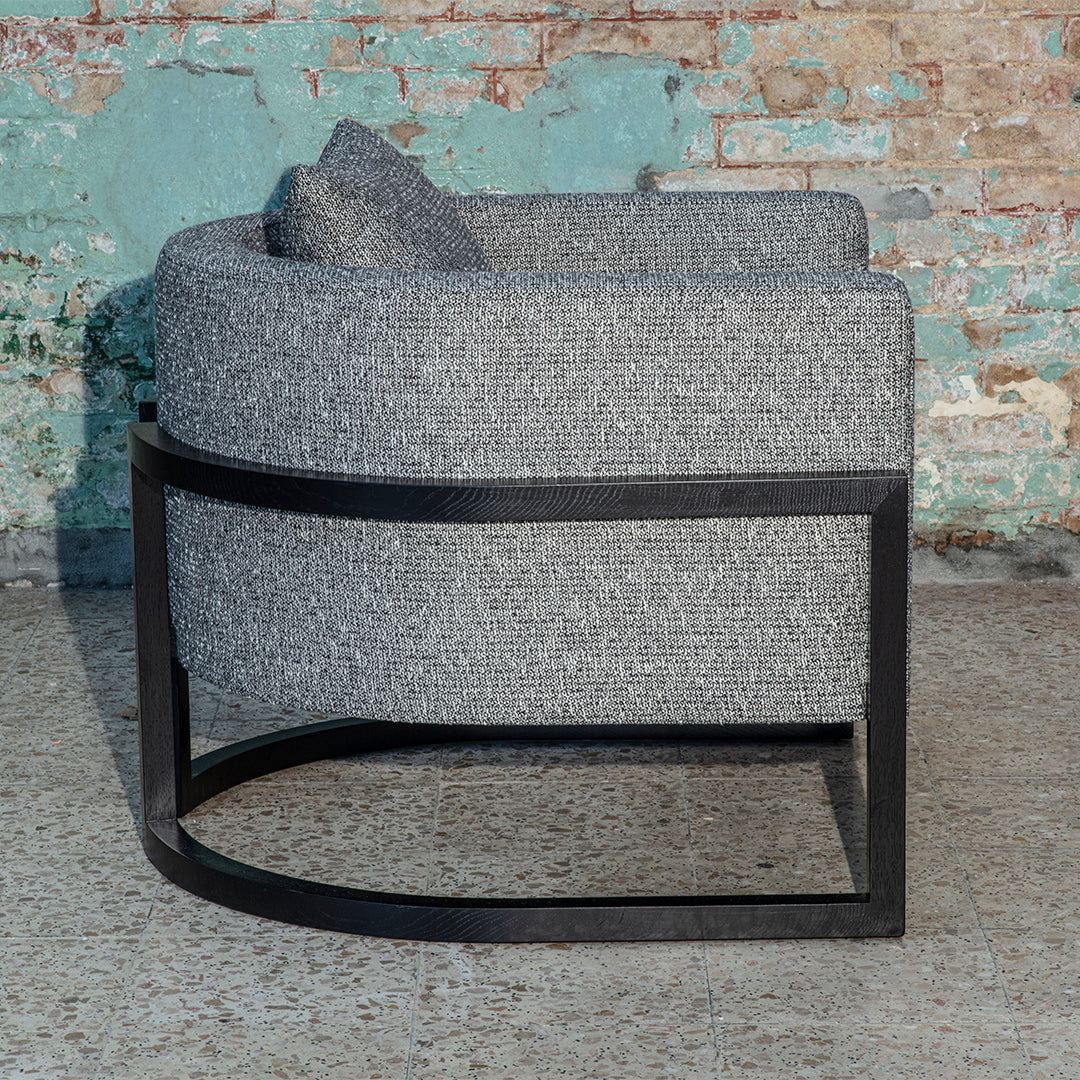 Stylish gray upholstered chair with a curved design and black metal base, featuring a subtle textured pattern.