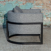 Stylish gray upholstered chair with a curved design and black metal base, featuring a subtle textured pattern.