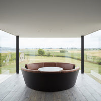 Modern circular sofa featuring dark brown leather and sleek black accents with a minimalist design.
