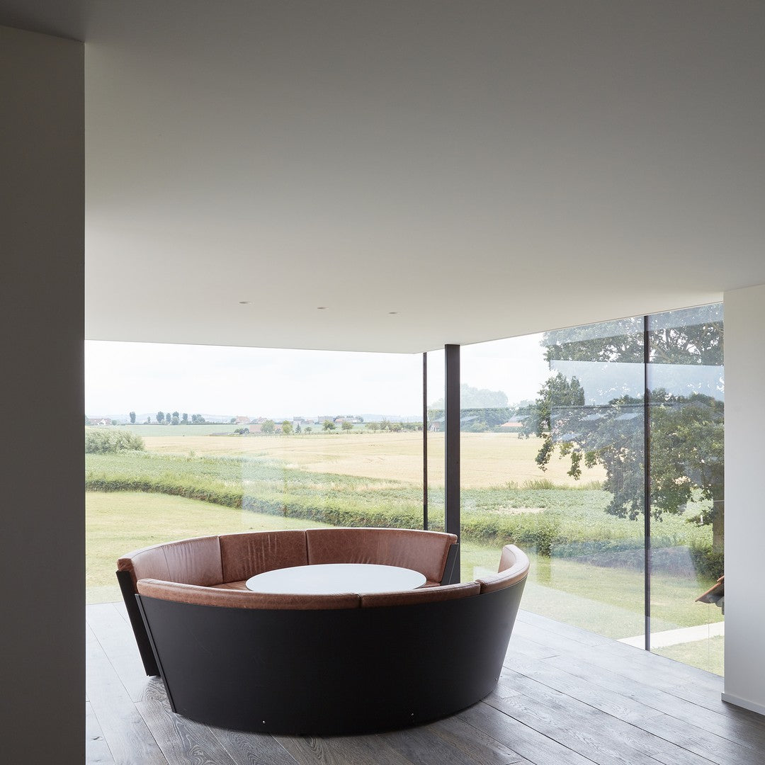 Round black and brown seating with a white tabletop, featuring a sleek modern design against a natural backdrop.