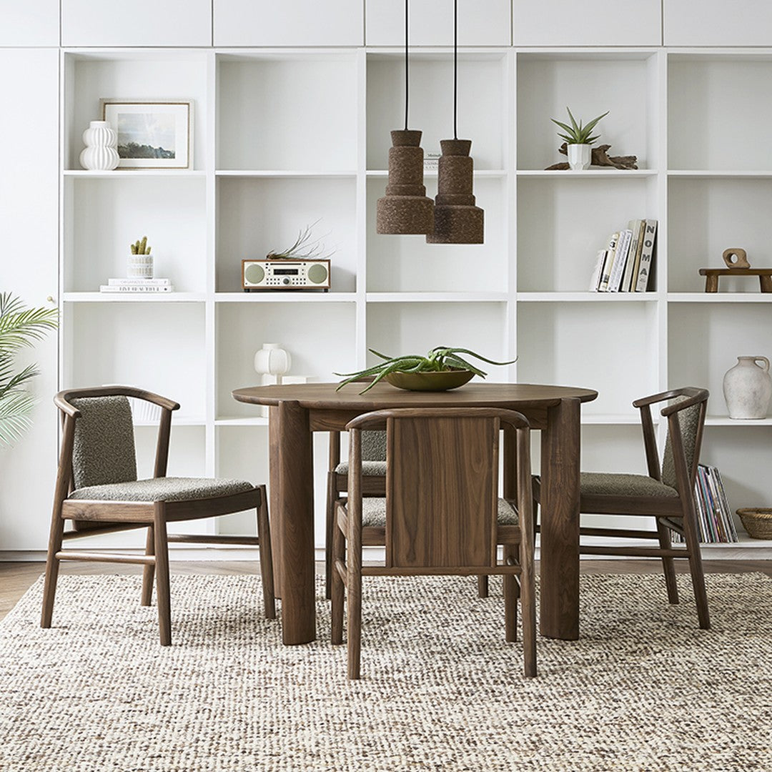 Wooden dining table with four chairs, featuring a neutral color palette and woven textures in a modern, minimalist setting.